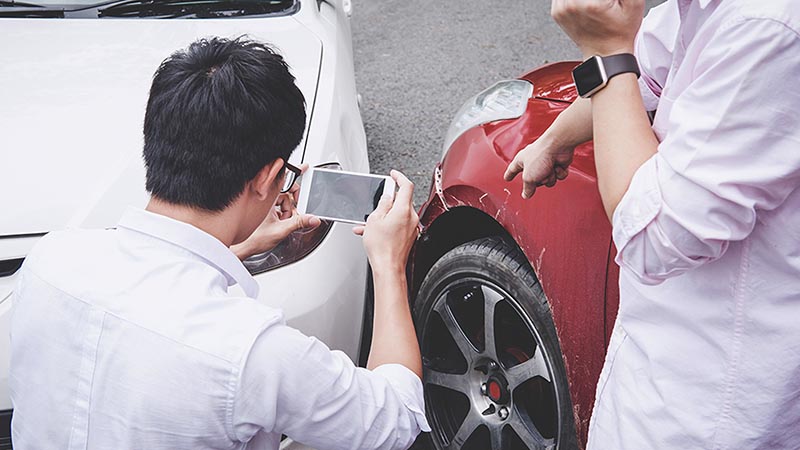 Man taking a photo of his damaged car after an accident